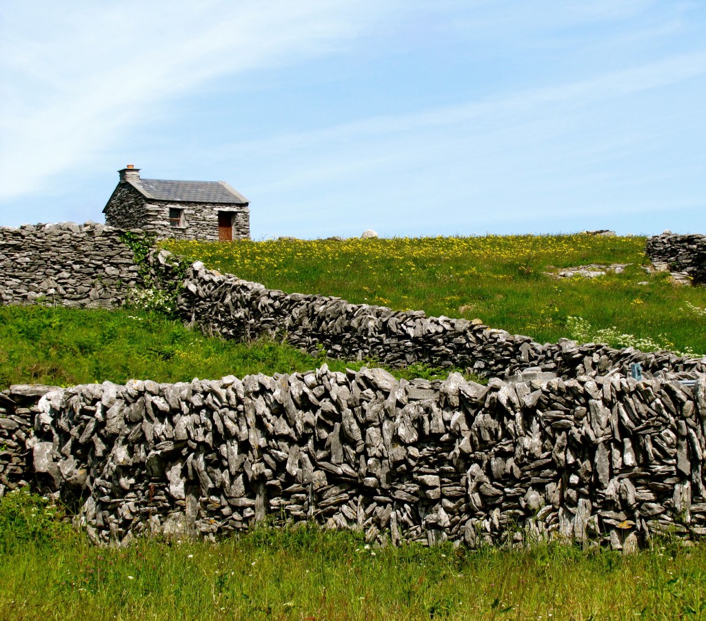 A neat looking stone house surrounded by stone walls.