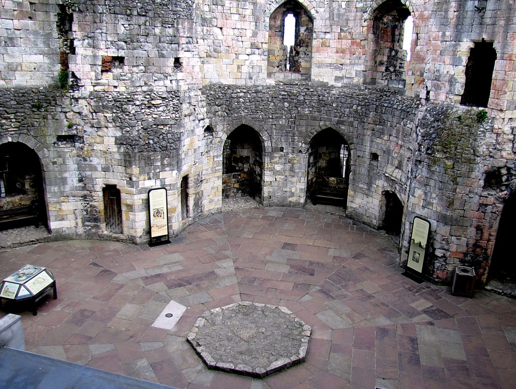 This is the interior of Clifford's Tower. Back before the gun accident, there were wooden floors and partitions in here, turning it into an actual livable location. The large slab in the centre was the base of the central pillar that reached up to the former ceiling, providing support for the higher floors.